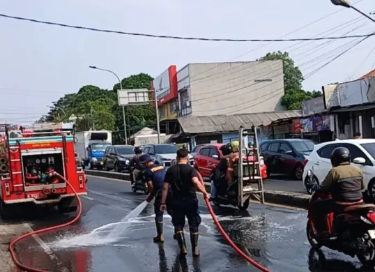 Petugas Damkar Kota Depok membersihkan jalan di Jalan Raya Parung-Ciputat yang terlumuri tumpahan oli. (Sumber: Dok. Istimewa)
