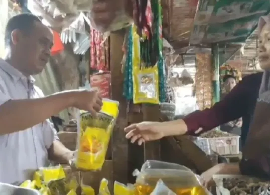 Pedagang minyak goreng di Pasar Badak Pandeglang saat melayani konsumen. (Sumber: Poskota/Samsul Fatoni)