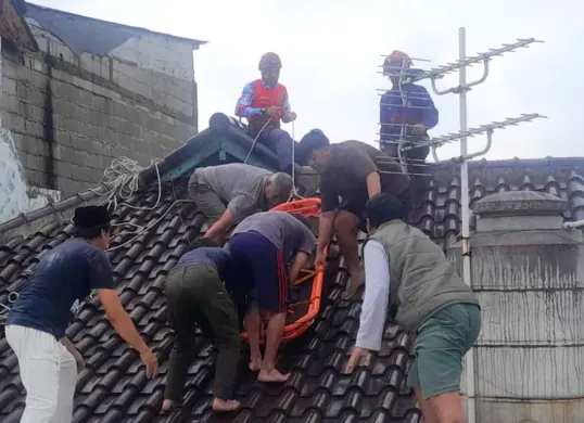 Petugas Damkar dibantu warga mengevakuasi korban yang meninggal saat membetulkan genteng rumah di Bogor. (Sumber: Damkar Bogor)