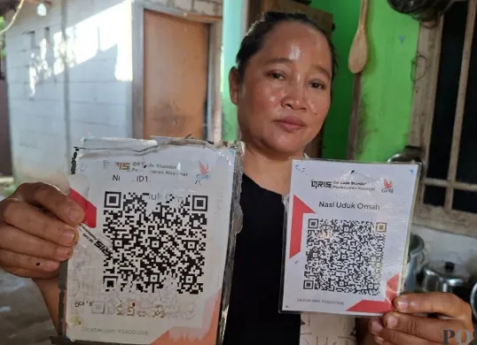 Warga Bedahan, Sawangan, Kota Depok, menunjukan QRIS palsu yang ditimpa pada kode QR asli, Rabu, 25 Februari 2026. (Sumber: Poskota/Angga Pahlevi)