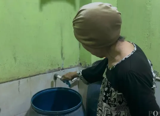 Harijani (64) warga RT 09 RW 03 Kelurahan Jembatan Besi, Tambora, Jakarta Barat, saat mencoba menyalakan kran yang airnya tidak mengalir dan keruh, Jumat, 9 Januari 2026. (Sumber: Poskota/Pandi Ramedhan)