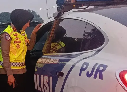 Kompol Darmawati, Kepala Induk PJR BSD Korlantas Polri, membantu mengevakuasi ibu hamil ke mobil patroli setelah kendaraan yang ditumpanginya mengalami overheat di KM 06 Ruas Tol BSD, Senin (13/7/2026). (Sumber: Istimewa)