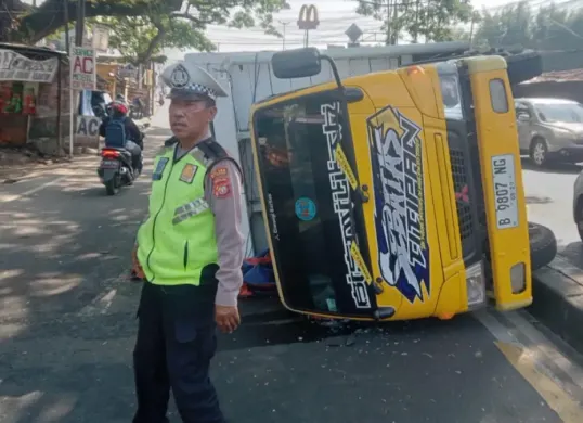 Petugas Lantas Polsek Beji melakukan pengaturan lalu lintas di Jalan Raya Bojongsari mengucari kemacetan akibat ada truk terguling, Rabu siang, 15 Juli 2026. (Sumber: Poskota/ Angga)