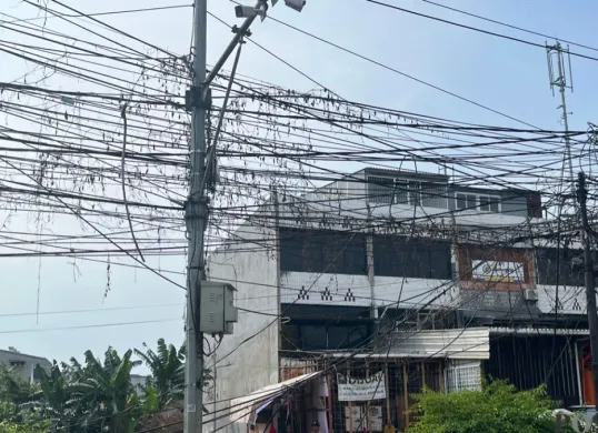 Warga sedang membenahi kabel menjuntai akibat tersenggol truk besar di Jalan Peta Selatan dan Jalan Peta Barat, Kalideres, Jakarta Barat, Selasa 23 Juni 2026. (Sumber: Poskota/Pandi Ramedhan)