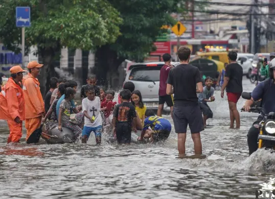 Warga melintasi genagan banjir di Jalan Bendungan Hilir, Jakarta Selatan, Minggu, 8 Maret 2026. (Sumber: Poskota/Bilal Nugraha Ginanjar)