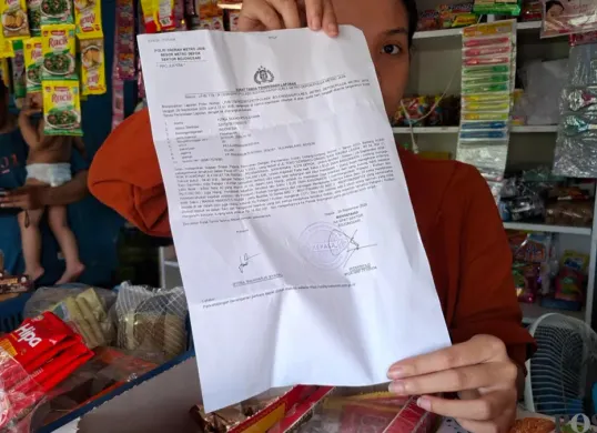 Pemilik Toko Sembako menunjukan laporan polisi setelah menjadi korban pencurian. (Sumber: Poskota/Angga)