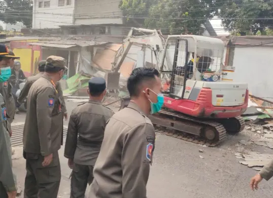 Satpol PP Kota Depok menggunakan alat berat eksavator membongkar bangunan liar dan PKL di Cimanggis, Kota Depok. (Sumber: Satpol PP Depok)