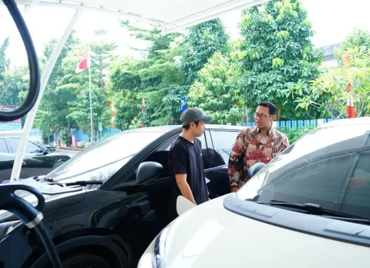 Senior Manager Niaga dan Manajemen Pelanggan PLN UID Jakarta Raya, Wira Bhakti Dharma berbincang dengan pengguna mobil listrik yang tengah mengisi daya kendaraannya di SPKLU Kantor PLN UP3 Cempaka Putih. (Sumber: Dok. PLN UID Jakarta Raya)