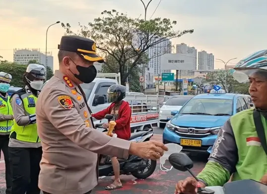 Kapolres Metro Depok, Kombes Pol Christian Rony Putra membagikan masker kepada pengguna kendaraan bermotor tidak bermasker di jalan. (Sumber: Polres Metro Depok)