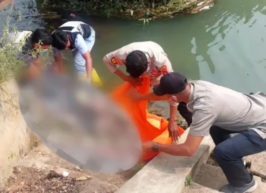 Petugas tengah melakukan proses evakuasi mayat pria di aliran irigasi. (Sumber: Polresta Serang Kota)
