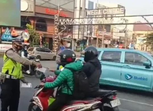 Petugas Lantas Polsek Cinere membagikan masker ke pengguna jalan di Jalan Raya Cinere. (Sumber: Satlantas Polsek Cinere)