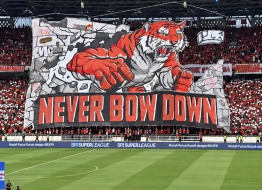Koreografi tiga dimensi The Jakmania bertuliskan “Never Bow Down” menghiasi tribune timur SUGBK saat Persija menghadapi Persib, Sabtu (12/9/2026). (Sumber: Instagram)