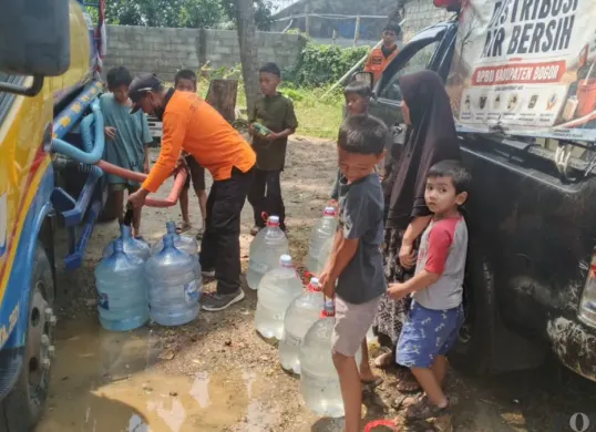 Petugas bantuan memberikan air bersih kepada warga saat situasi kemarau yang menyebabkan krisis air bersih di Depok. (Sumber: Pos Kota/ Angga)